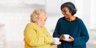 two women with cup of tea and laughing
