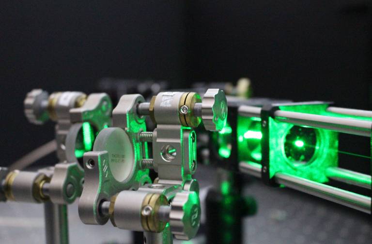 Photo of a green laser on an optical table in a lab.