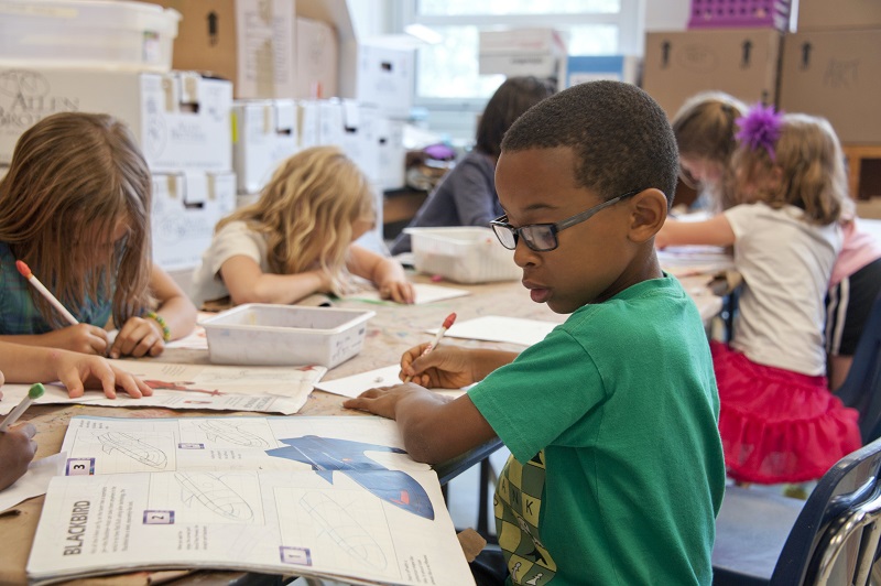 children in a classroom, reading and writing 