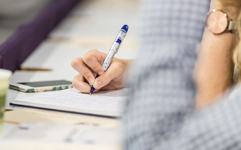 Hand holding pen writing on document on desk