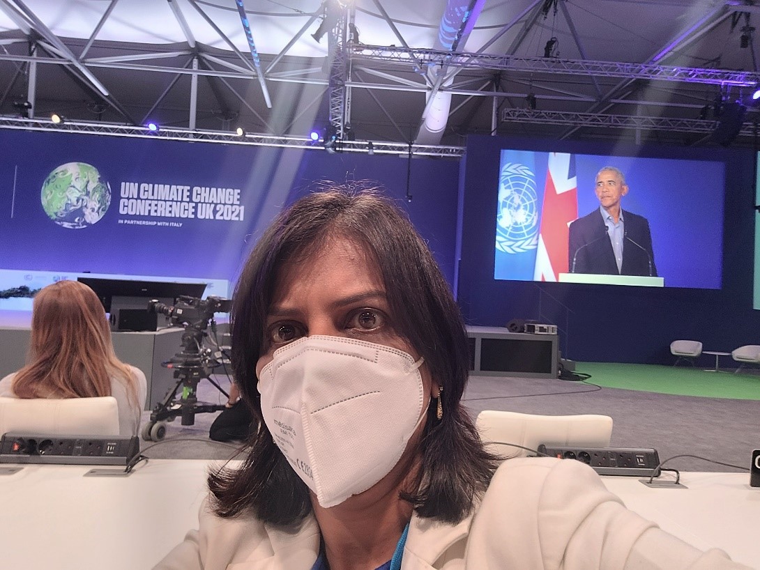 Dr Priti Parikh at the COP26 climate conference standing in front of the screen showing Barack Obama's talk