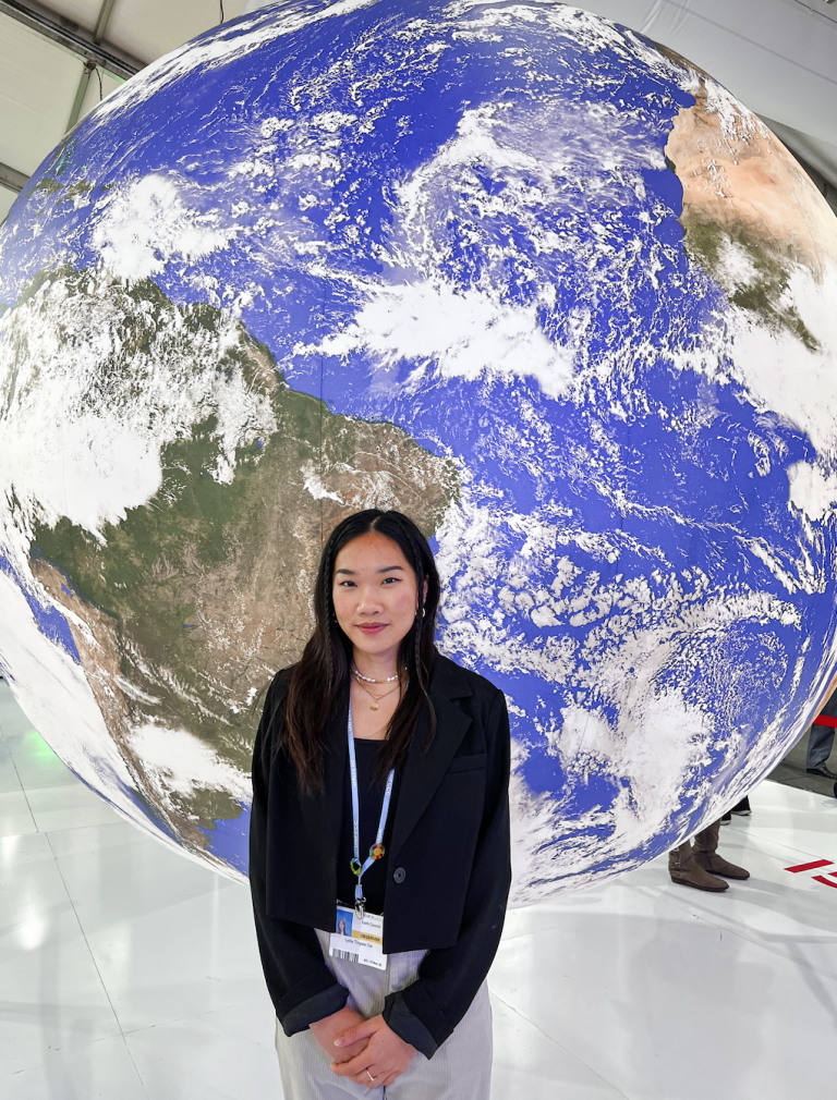 lydia stands in front of a giant globe at cop27