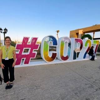 Kate stands in front of COP27 sign