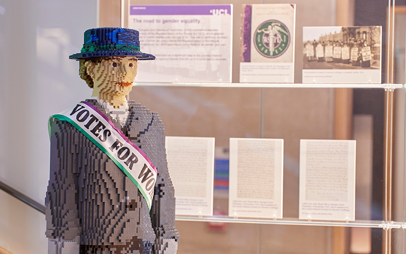 an image of the lego suffragette Hope with a UCL Exhibition in a glass case in the background 