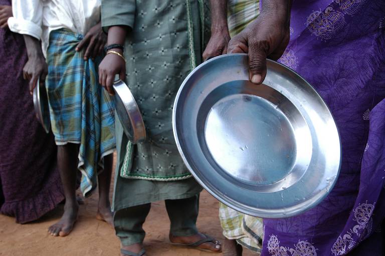 Hands holding empty plates as people queue for food