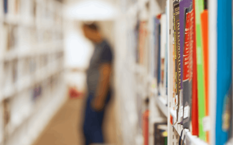 Blurred figure in between library shelves