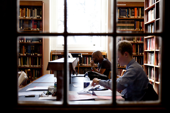 Two people sat at a desk in the library reading books
