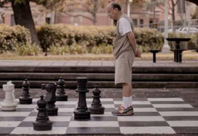 Man standing playing on park large sized chessboard