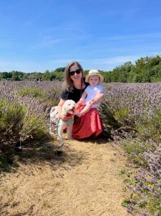 A woman holding a baby boy and with a dog at her feet, in a lavender field