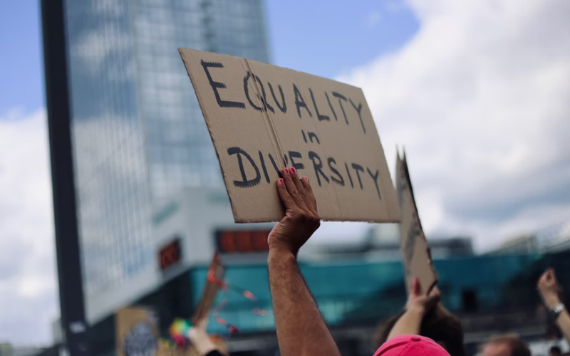 A person holding up a sign 'equality in diversity'
