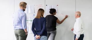 Four people standing near a whiteboard