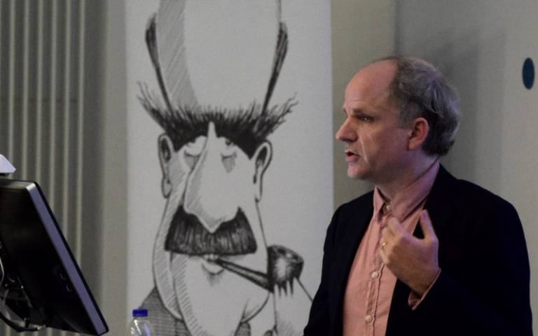 Prof. John Tresch, speaking in front of a caricature of JBS Haldane
