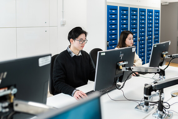 UCL students work at desktop computers.