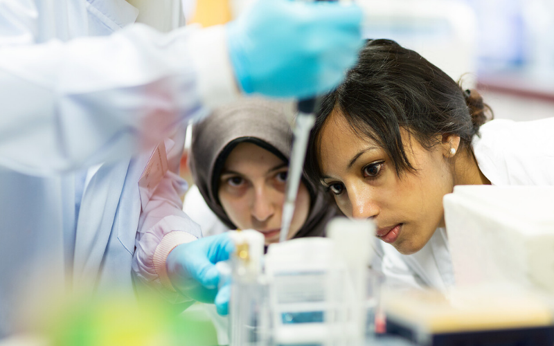 Two female students looking closely at an experiment in a lab