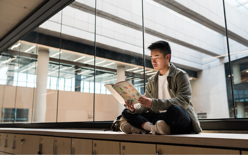 Male student reading a book in UCL East