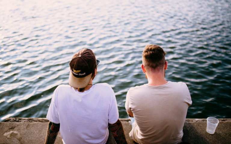 Two guy friends talking by the water