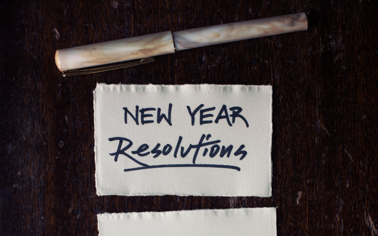 Piece of paper titled new year resolutions next to a pen