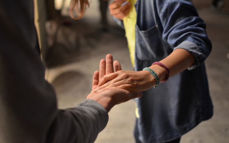 Young people holding hands supportively, helping others