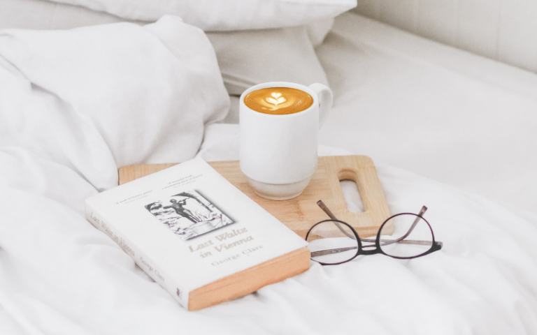 Book, coffee and glasses on a bed