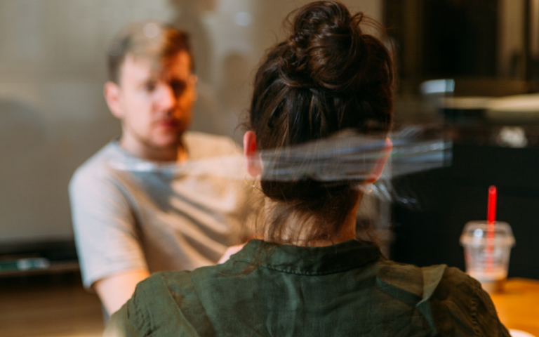 Two people having a meeting behind a glass screen