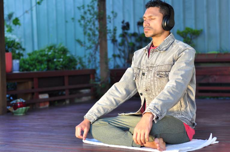 Person wearing headphones sitting with legs crossed and eyes closed