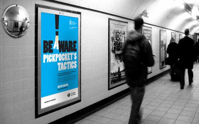 man walks through the tube station with advert about pick pockets showing