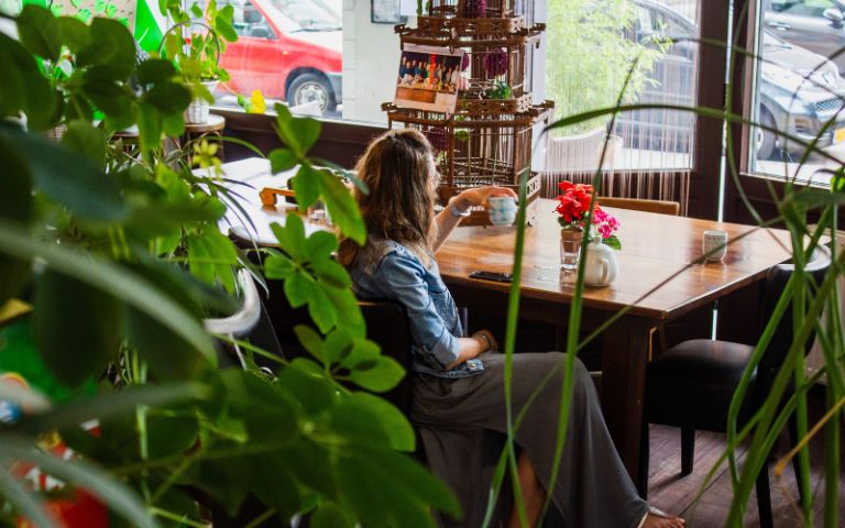 woman sitting in leafy cafe