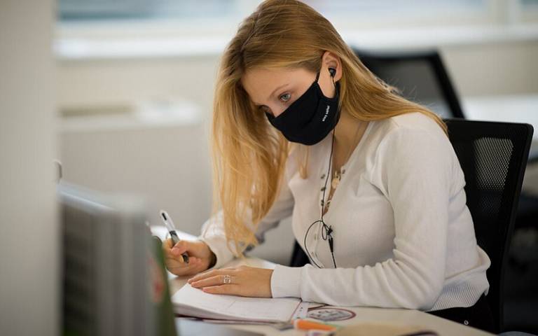 Woman with mask studying at PC