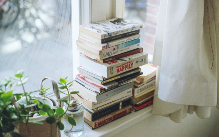 Pile of assorted books on window sill