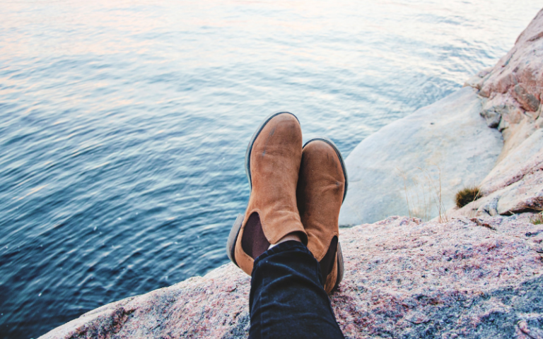 shoes over edge of cliff overlooking sea