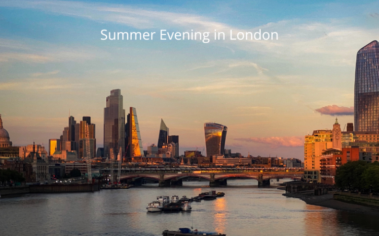 Panoramic view of the City of London with boats on the river and the buildings basked in a warm orange glow