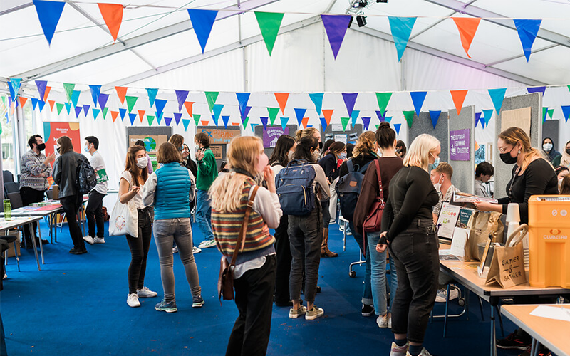 Students in a marquee, looking at welcome fair stalls