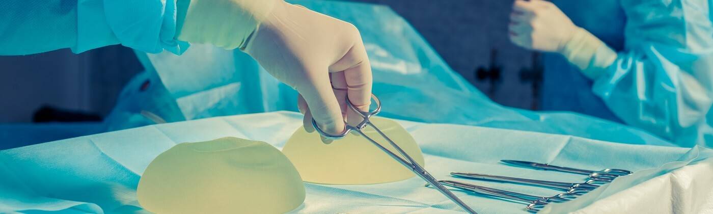 A gloved surgeon takes scissors from an operating table