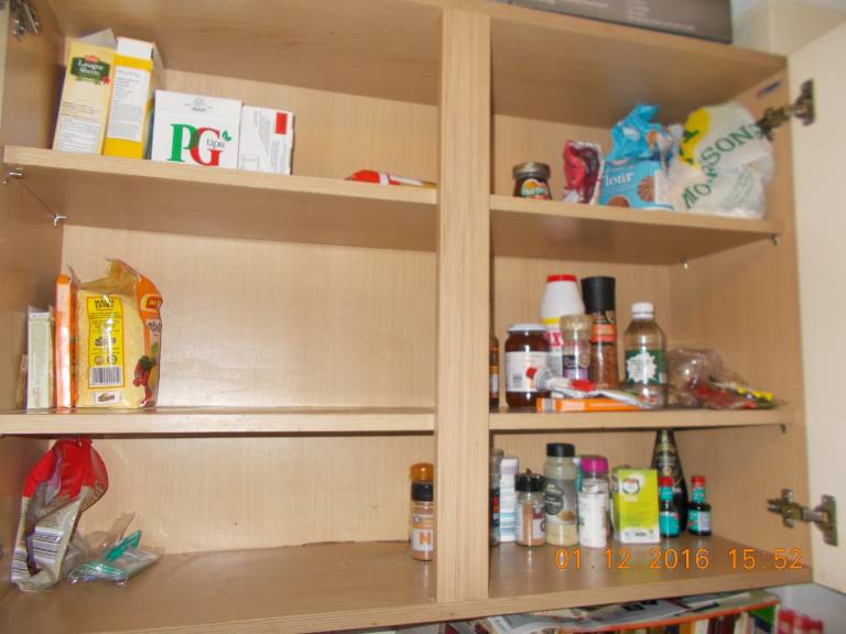 Kitchen cupboard with few items on the shelves.