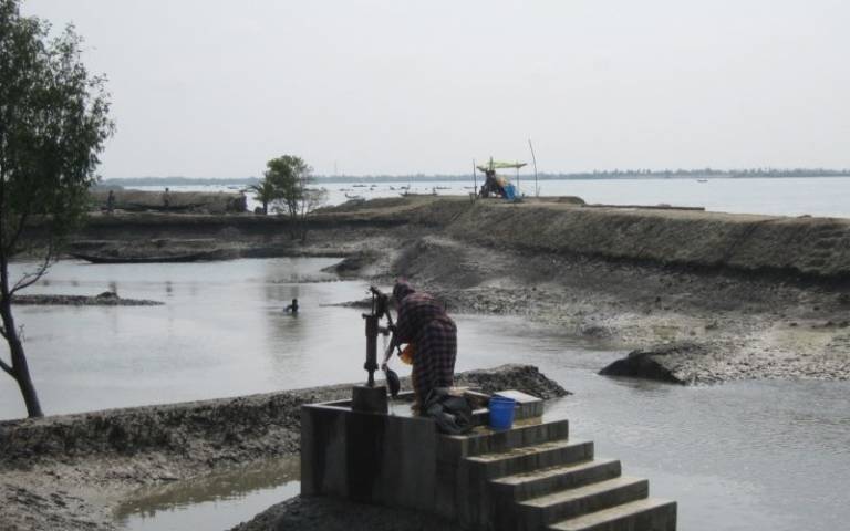 A woman pumps fresh deep groundwater in Gabura of coastal Bangladesh while surrounded by brackish surface water
