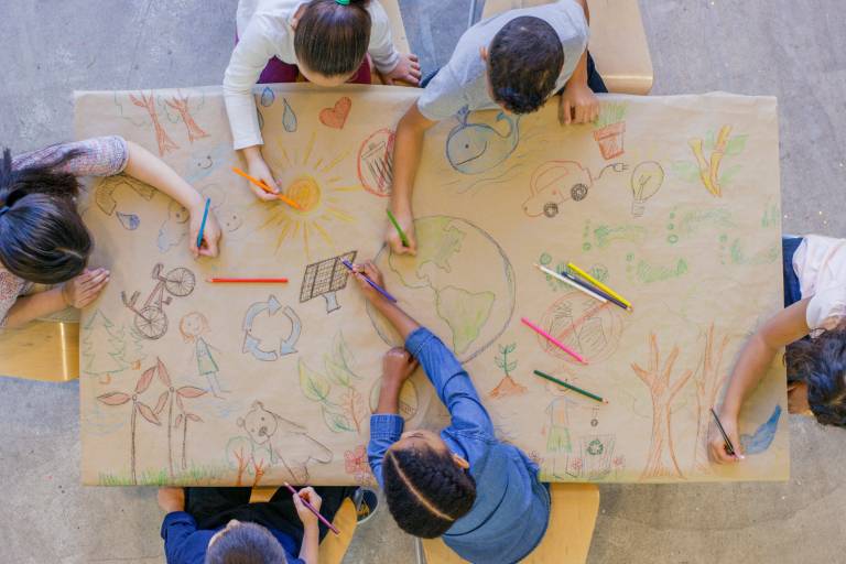 Arial shot of kids drawing on a large sheet of paper