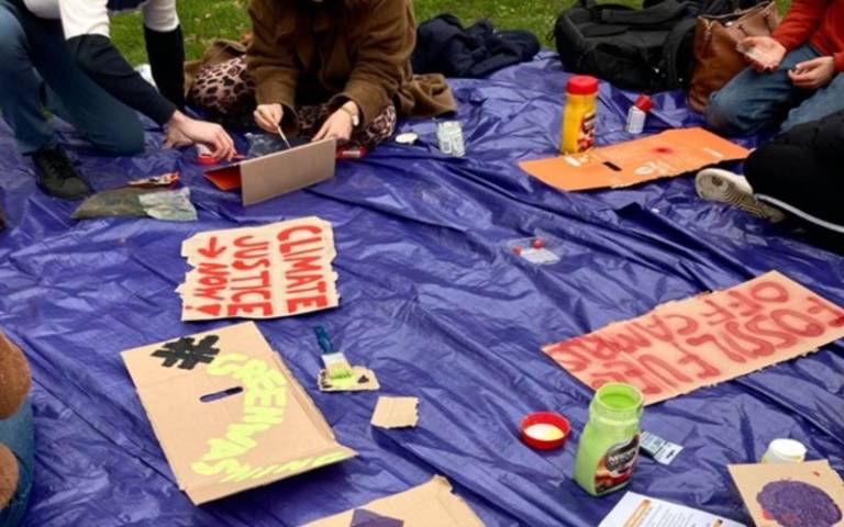 A close-up of students' hands as they create hand-painted signs and banners