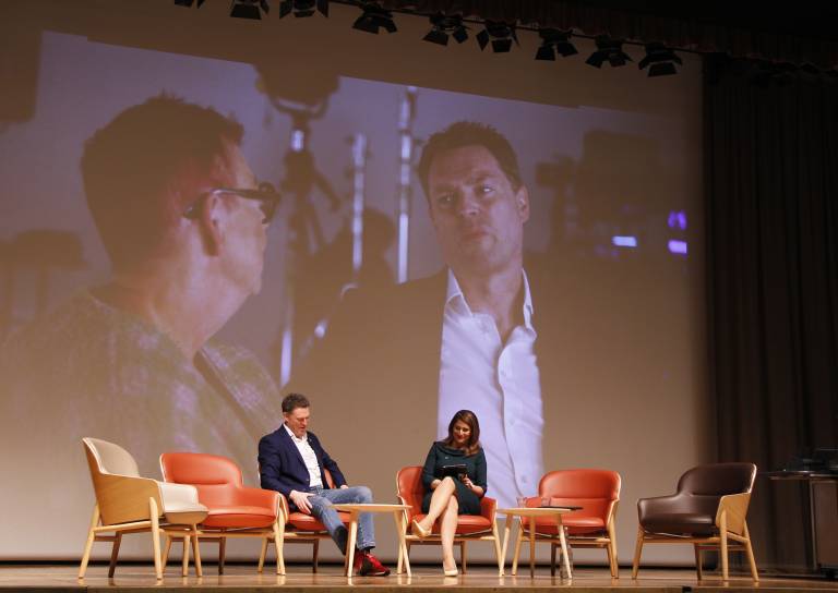 Prof. Mark Maslin giving fireside chat on stage, with Jo brand video in the backgroun
