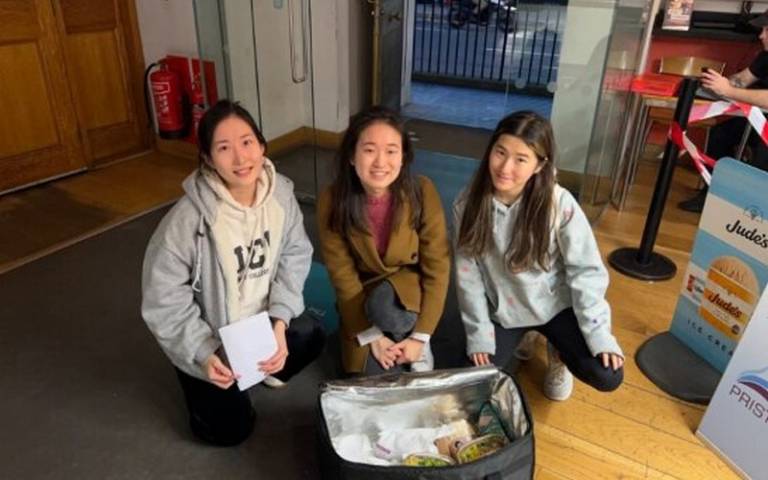 3 women smiling next to a box of rescued food waste