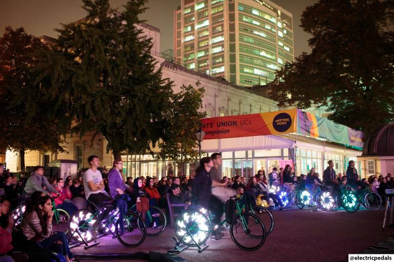 Students cycling on bikes to power the bike-powered cinema.