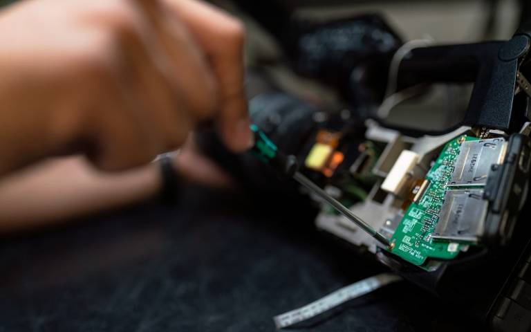 hand repairing an electronic item with a screw driver