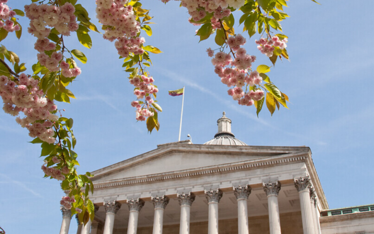 Photo of the UCL Portico taken through the branches of a blossom tree