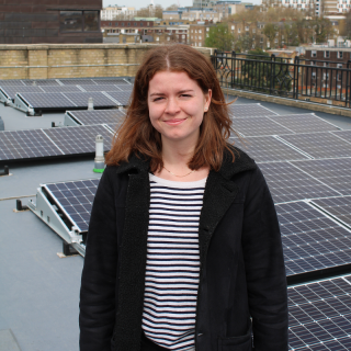 Ali from the Clean Energy Projects Society in front of solar panels