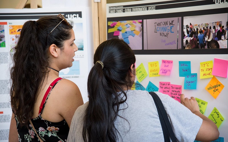 Two students viewing a board with postit notes