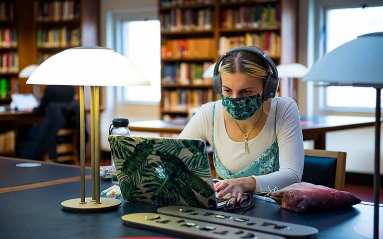 Student on laptop wearing headphones and mask