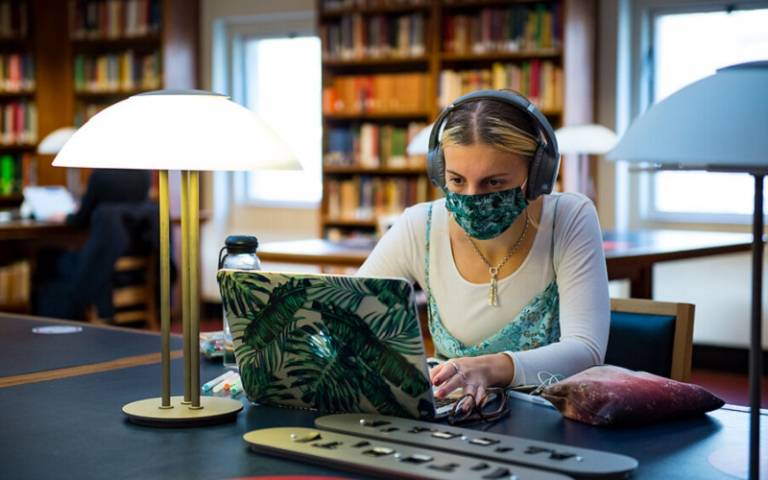 Student in a mask at her laptop in the library