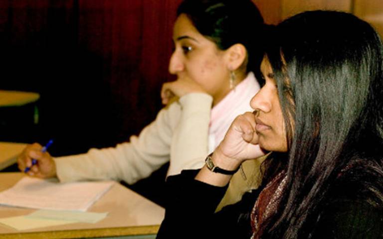 Two female students sitting in a classroom listening