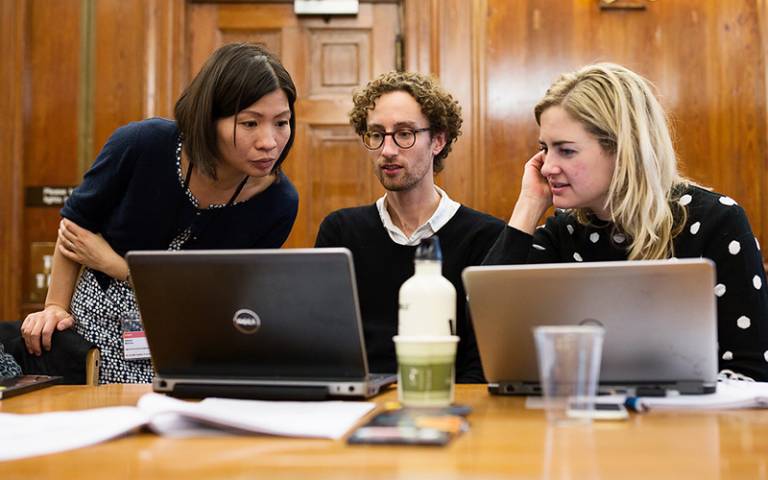 Three staff members in conversation at a laptop