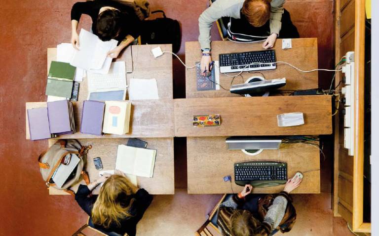 Students pictured from above sitting around a table with books and papers