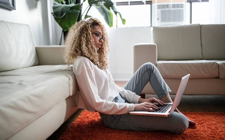 Woman sitting on floor typing on a laptop. Credit: Thought Catalog/ Unsplash